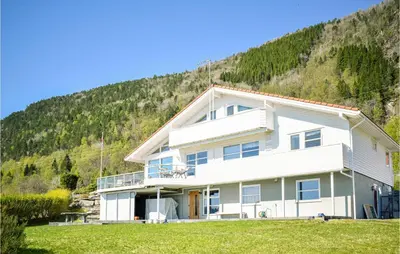 a large white house with a hill in the background at 5 Bedroom Beach Front Home In Lavik in Lavik