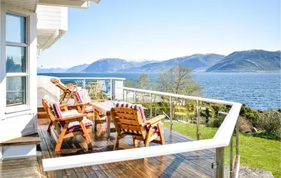 a balcony with chairs and a table and a view of the water at 5 Bedroom Beach Front Home In Lavik in Lavik
