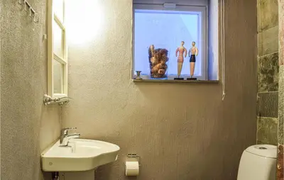 a bathroom with a sink and a window with two men on a window sill at 3 Bedroom Beautiful Home In Eikefjord in Eikefjord