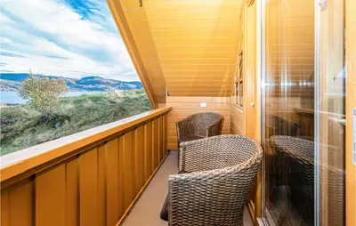 a balcony with two chairs and a window on a train at Beach Front Home In Kvamsøy in Sandvik