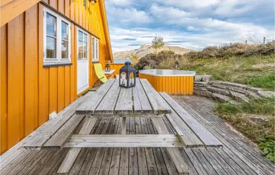 a person sitting in a chair on a wooden deck next to a house at Beach Front Home In Kvamsøy in Sandvik