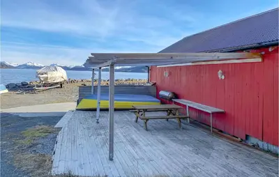 a red building with a bed and a picnic table at Lovely Apartment In Ellingsøy in Myklebost