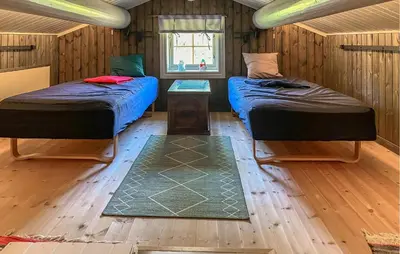two beds in a room with wooden walls and wooden floors at Pet Friendly Home In Rena With Wifi in Rena
