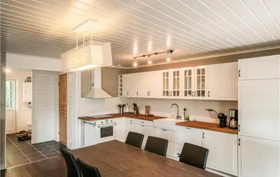 a kitchen with white cabinets and a table and chairs at Gorgeous Home In Søre Osen With Wifi in Midskogberget