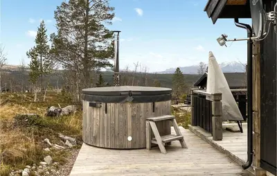 a wooden deck with a hot tub and a stool at Beautiful Home In Engerdal With Kitchen in Kvisla