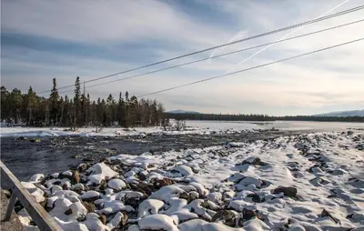 a river with snow on the rocks and a fence at Lovely Home In Drevsjø With Lake View in Drevsjø