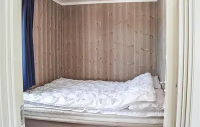 an unmade bed in a room with a wooden wall at 3 Bedroom Amazing Home In Jaren in Jaren