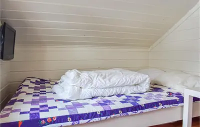 a bed with a comforter on it in a room at Awesome Home In Nord-Torpa With Kitchen in Nord Torpa