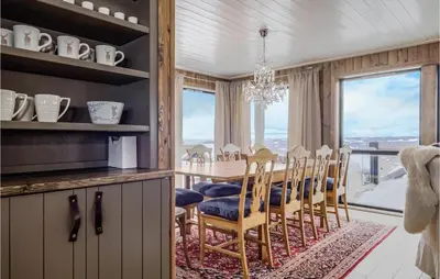 a dining room with a table and chairs and a large window at 4 Bedroom Lovely Home In Øyer in Øyer