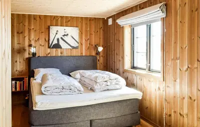 a bedroom with a bed with wooden walls and a window at 4 Bedroom Beautiful Home In Øyer in Øyer