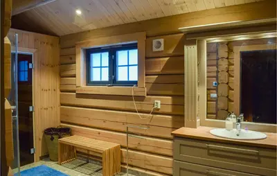 a bathroom with wooden walls and a sink and a window at Beautiful Home In Øyer With Sauna in Øyer