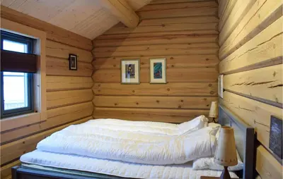 a bed in the corner of a log cabin at Beautiful Home In Øyer With Sauna in Øyer