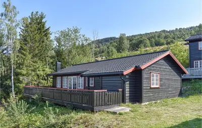 a log cabin with a deck in the woods at Amazing Home In Øyer With Kitchen in Øyer