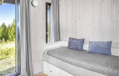 a bed with blue pillows in a room with a window at Beautiful Home In Øyer With Sauna in Øyer