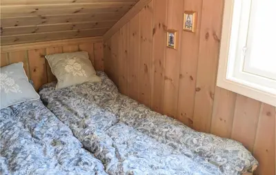 a bed in a room with wooden walls and a window at Amazing Home In Mesnali With Wifi in Mesnali