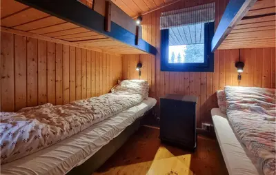 two beds in a room with wooden walls and a window at Amazing Home In Sjusjøen With Sauna in Sjusjøen