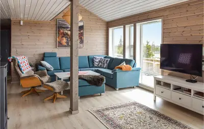 a living room with a blue couch and a tv at 4 Bedroom Beautiful Home In Sjusjøen in Sjusjøen