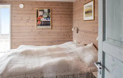 a bedroom with wooden walls and a bed with a blanket at 4 Bedroom Beautiful Home In Sjusjøen in Sjusjøen