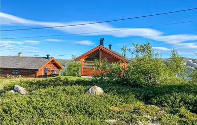 a log cabin on a hill next to a house at 1 Bedroom Nice Home In Geilo in Geilo