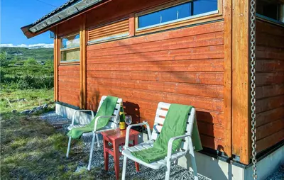three chairs and a table next to a cabin at 1 Bedroom Nice Home In Geilo in Geilo