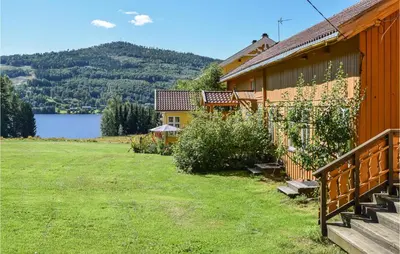 a house with a large yard next to a lake at Bjertnes Turistgård in Noresund