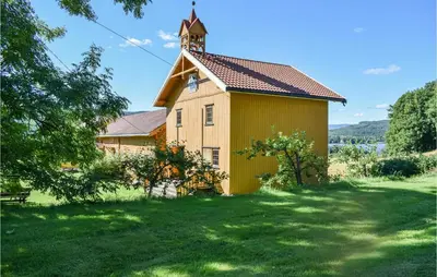a church with a tower on top of a grass field at Bjertnes Turistgård in Noresund