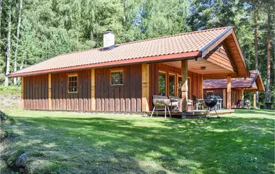 a wooden cabin with a grill in a yard at Bjertnes Turistgård in Noresund
