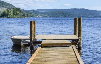 a dock with a boat and a bench on a lake at Bjertnes Turistgård in Noresund
