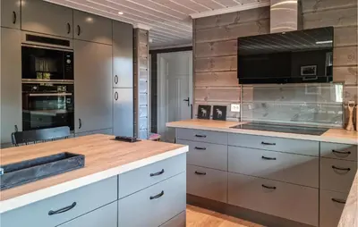 a kitchen with white cabinets and a flat screen tv at Stunning Home In Hovden I Setesdal in Hovden