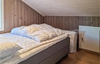 an unmade bed in a room with wooden walls at Stunning Home In Hovden I Setesdal in Hovden
