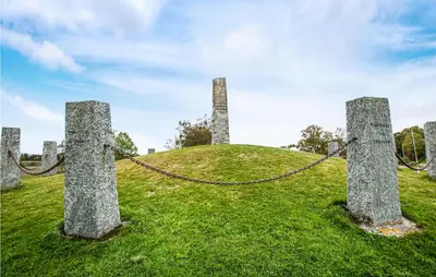 a grassy hill with stone pillars with a chain at Stunning Home In Frosta
