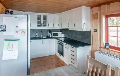 a kitchen with white cabinets and a refrigerator at Nice Home In Malm With Lake View in Malm