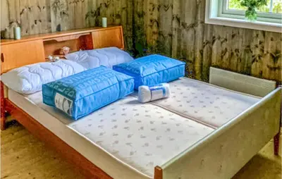 a large bed with four blue pillows on it at Nice Home In Beitstad With Kitchen in Sunnan