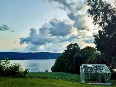 a greenhouse sitting in the grass next to a lake at Randsfjord house in Gran