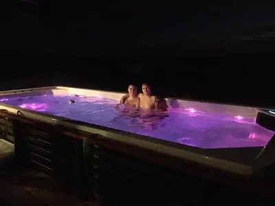 two people sitting in a jacuzzi at night at Trollvang, hytte med pool og sauna in Dovreskogen