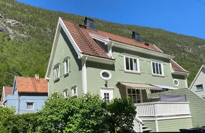 a green and white house with a mountain in the background at Tveitopark Apartments A in Rjukan