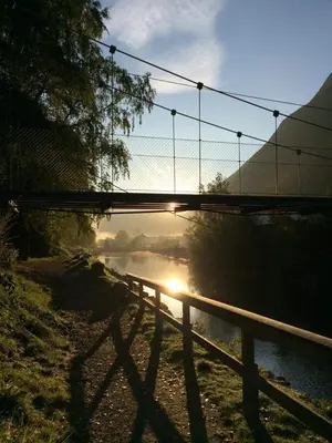 a fence next to a river with a bridge at Tveitopark Apartments A in Rjukan