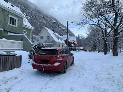 a red car parked in a snow covered street at Tveitopark Apartments A in Rjukan