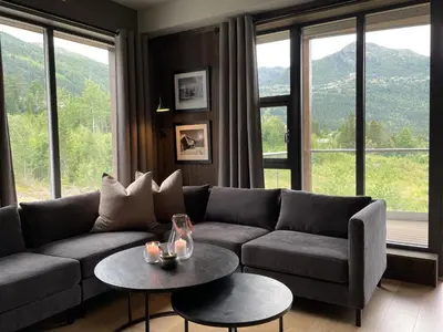 a living room with a couch and tables and windows at Snøya Lodge in Hemsedal