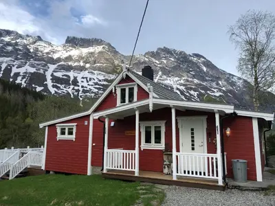 a red house with a mountain in the background at Solvang World Heritage Camping in Eidsdal