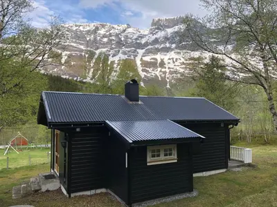a black shed with a mountain in the background at Solvang World Heritage Camping in Eidsdal