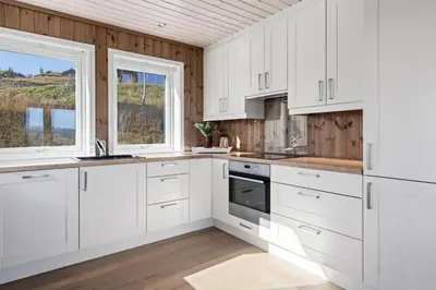 a white kitchen with white cabinets and a window at Golsfjellet - Bualie, milevis med sykkelveier, fiske og vannaktivitet, ski inn/ut til alpinanlegg og langrennsløyper. in Gol