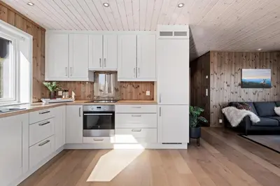 a kitchen with white cabinets and wooden walls at Golsfjellet - Bualie, milevis med sykkelveier, fiske og vannaktivitet, ski inn/ut til alpinanlegg og langrennsløyper. in Gol