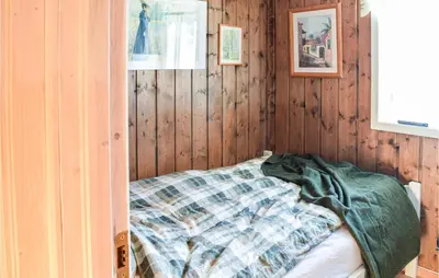 a bedroom with wooden walls and a bed with a blanket at Sjusjøvegen 1892 in Sjusjøen