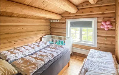 a log cabin bedroom with a bed and a window at Nice Home In Vinstra With Kitchen in Vinstra