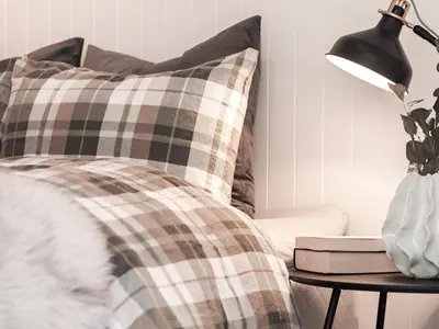 a bed with a plaid pillow and a lamp on a table at 9 person holiday home in Geiranger-By Traum in Geiranger