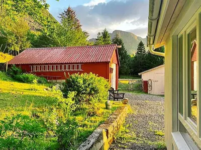 a red barn sitting next to a house at 6 person holiday home in MIDSUND-By Traum in Aukra