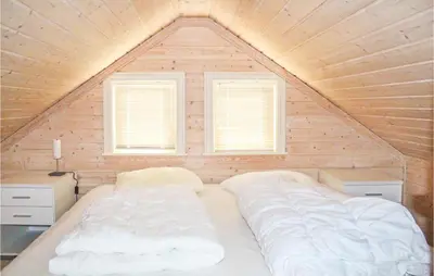 a large bed in a room with two windows at 4 Bedroom Nice Home In Sogndal in Sogndal