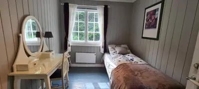 a bedroom with a bed and a desk and a mirror at VILLA HASSELBAKKEN in Eidsvoll