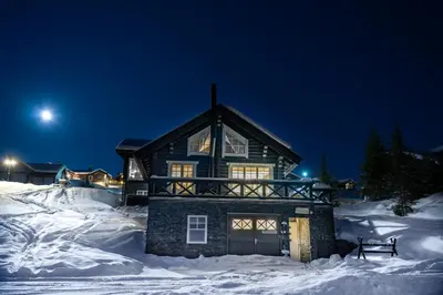 a log cabin in the snow at night at Hafjell tømmerhytte 4B in Hafjell